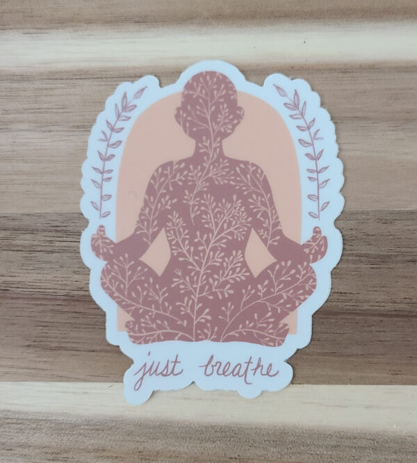 orange and white sticker of person meditating with phrase just breathe on bottom of sticker