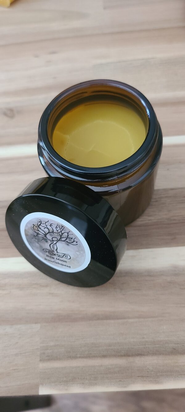 small jar of muted yellow healing winter hand salve open on a wooden table